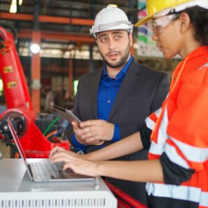 Young Africa American industrial robotic engineer talk with businessman and control robotic arm by using laptop in the factory. Manager is interested on this project. Technology and innovation concept Young Africa American industrial robotic engineer talk with businessman and control robotic arm by using laptop in the factory. Manager is interested on this project. Technology and innovation concept